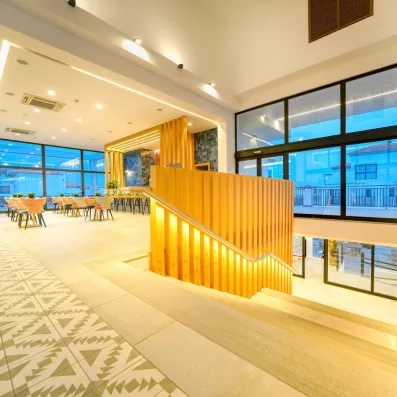 Un grand hall lumineux, mettant en valeur un escalier central original en bois éclairé.