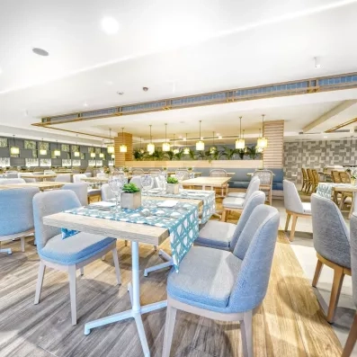 Une salle de restaurant lumineuse, avec des chaises et des tables parfaitement dressées.