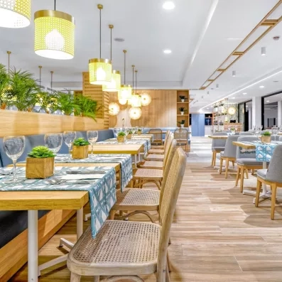 Une perspective élégante du restaurant mettant en avant des luminaires suspendus et un mobilier en bois clair.