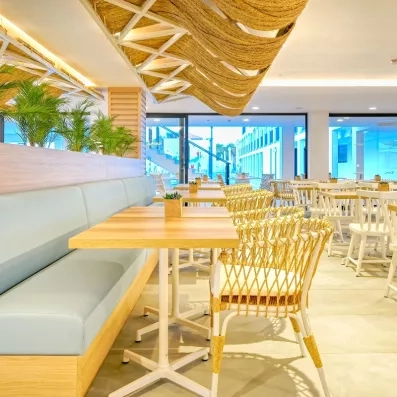 Un espace de restauration intérieur lumineux et moderne avec du mobilier en bois et des banquettes.