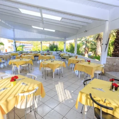 restaurant extérieur couvert du soleil, avec des tables et des chaises en jaune pastel 