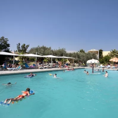 piscine extérieur avec fontaine colorée et un aqua parc au milieu et des gens qui nagent 
