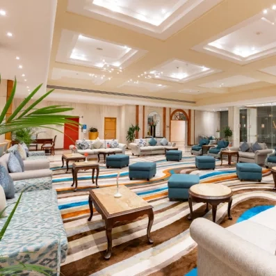 réception avec grande moquette colorée, des tabourets, fauteuils, tables basses