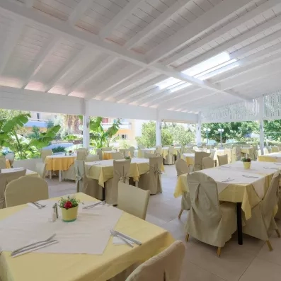 restaurant extérieur couvert du soleil, avec des tables et des chaises en jaune pastel 