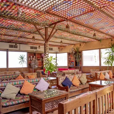 bar extérieur avec toit en bois, des banquettes avec motifs colorés