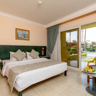 chambre double avec grand lit, tête de lit en bois vert, porte fenêtre donnant sur le jardin 