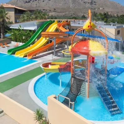 piscine, aqua park coloré, végétation autour et montagne au fond 