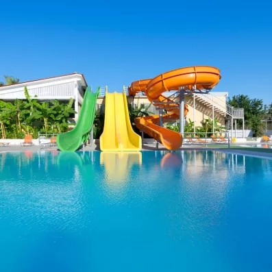 Piscine extérieur avec des toboggans aquatiques, de la végétation et des transats pour bronzer