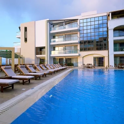 Bâtiment avec les terrasses donnant sur piscine extérieur de l'hôtel avec les transats et les parasols