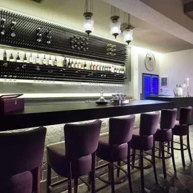 bar de l'hôtel avec des chaises hautes en violet sur le comptoir et des bouteilles pour décorer