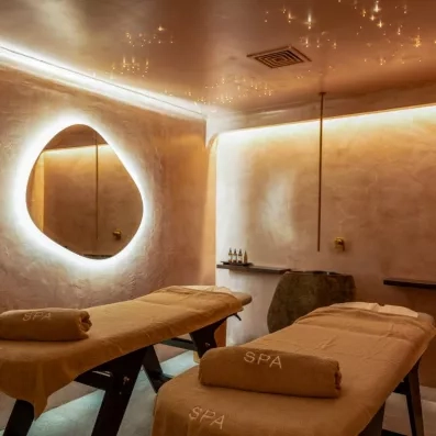 deux tables de massage au spa de l'hôtel avec un miroir accroché au mur 