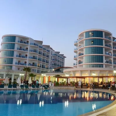 Une vue extérieure du complexe hôtelier illuminé avec sa piscine et ses façades.