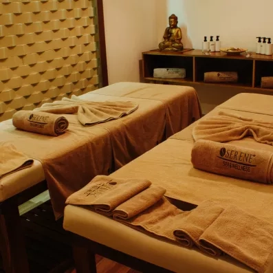 Une salle de massage présentant deux tables de soins préparées avec des serviette.