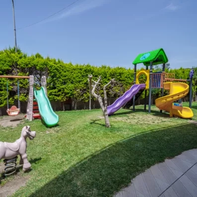 Une aire de jeux extérieure pour enfant avec plusieurs toboggans et une balançoire.