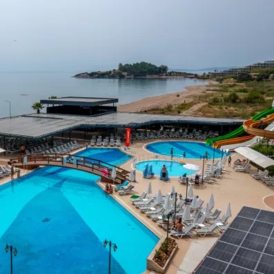 Un parc aquatique extérieur avec plusieurs piscines, des toboggans et une vue sur la mer.