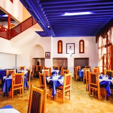 Salle restaurant de l'hôtel avec un plafond en bois bleu, tables et chaises 