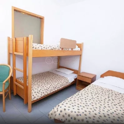 Chambre quadruple, lits superposé et lit double avec table de nuit et chaise