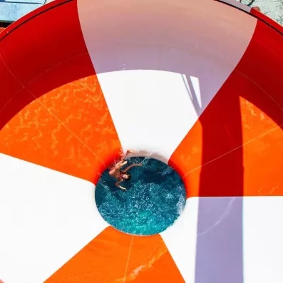 tourbillon blanc et orange aquapark, petite fille qui glisse et s'amuse dans le jeu d'eau