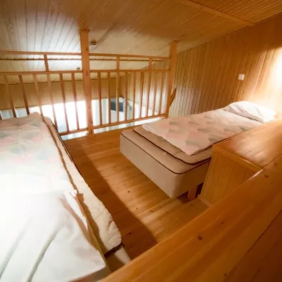 Espace nuit en mezzanine sous les toits pour un hébergement familial authentique en Laponie finlandaise.