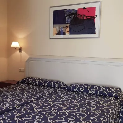 Une chambre avec lit double confortable avec un couvre-lit à motifs bleus.