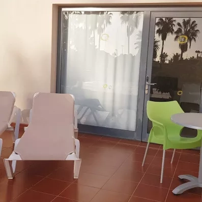 Un terasse privé avec des chaises longues et du mobilier de jardin moderne devant une baie vitrée.