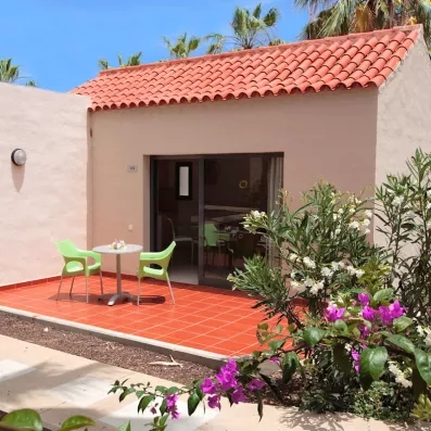 Vue de la terrasse d'une chambre, avec une table de jardin et une végétation fleurie.