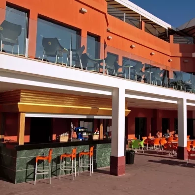 Un bar de terrasse moderne, situé au pied d'un bâtiment aux façades orange vif.