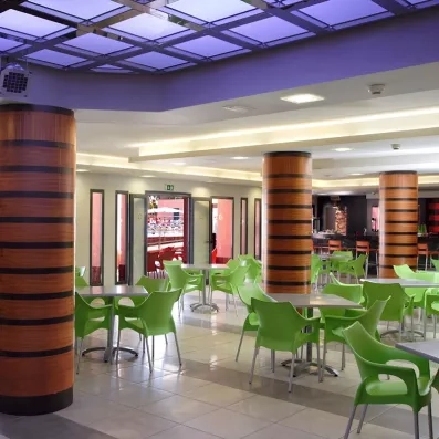Une grande salle commune avec des chaises et un plafond décoratif violet.