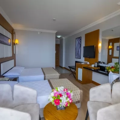 chambre avec lits de profil et tables basse et chaises avec un bouquet de fleur