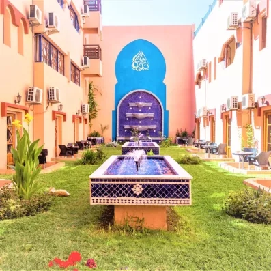 Patio avec jardi au milieu et deux fontaines d'eau avec le bâtiment des chambres tout autour