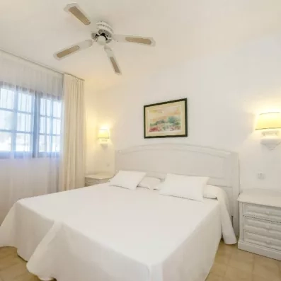 Une chambre d'hôtel minimaliste avec un lit double fait de draps blancs.