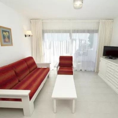 Un salon minimaliste avec un canapé-lit, un fauteuil assorti, une table basse et des baies vitrées.