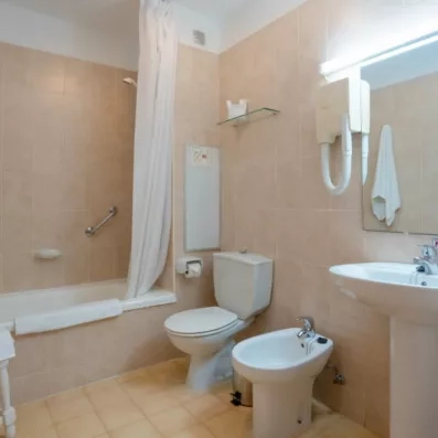 Une salle de bain fonctionnelle avec une baignoire, un toilette et un grand miroir.