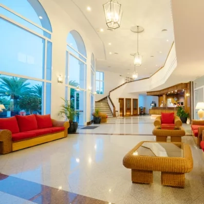 Un hall d'hôtel spacieux et lumineux avec de grands canapés, des tables basses en bois.