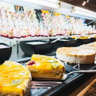 Une rangée de verrines de dessert est disposée sur une étagère en verre.