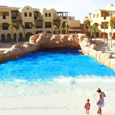 Piscine à vagues artificielle avec rochers et bâtiments typiques au Mondi Club Stella Garden, Égypte.