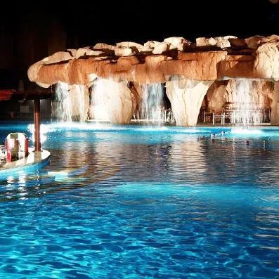 Grotte artificielle avec cascades éclairées dans la piscine de nuit au Mondi Club Stella Garden.