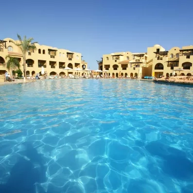 Piscine aux eaux cristallines entourée de bâtiments de vacances sous le soleil d'Hurghada, Égypte.