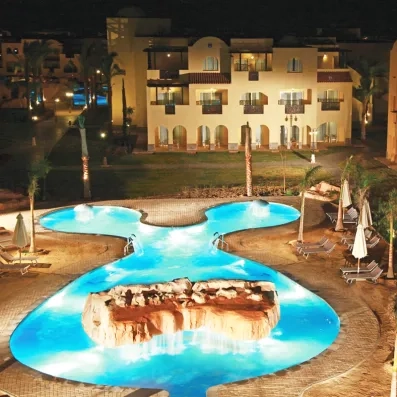 Éclairage nocturne spectaculaire de la piscine et des façades de l'hôtel Mondi Club Stella Garden.