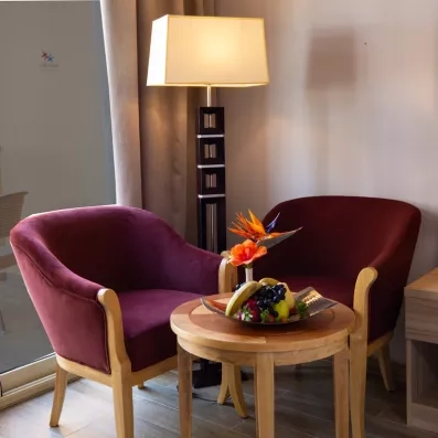 Coin salon cosy avec fauteuils bordeaux, corbeille de fruits et balcon vue mer à Hurghada.