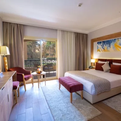 Chambre premium spacieuse avec balcon ensoleillé, mobilier en bois et décoration élégante au bord de la Mer Rouge.