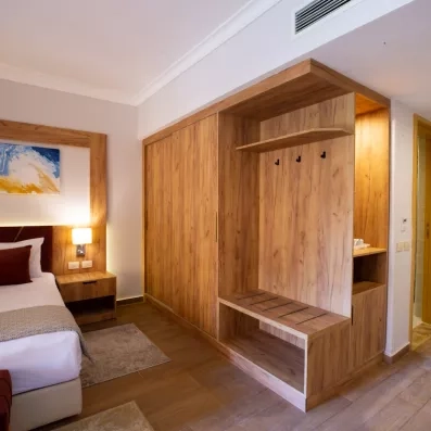 Dressing en bois clair et entrée d'une chambre de luxe lumineuse au Stella Beach, Égypte.
