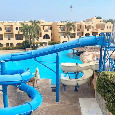 Piscine avec toboggans bleus et bâtiments ocres au Mondi Club Stella Garden, Hurghada, Egypte.