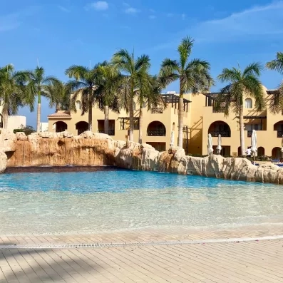 Bassin de détente avec cascade artificielle, palmiers et architecture orientale à Hurghada, Egypte.