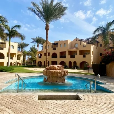 Piscine du Mondi Club Stella Garden à Hurghada, Égypte, avec palmiers et toboggans sous ciel bleu.