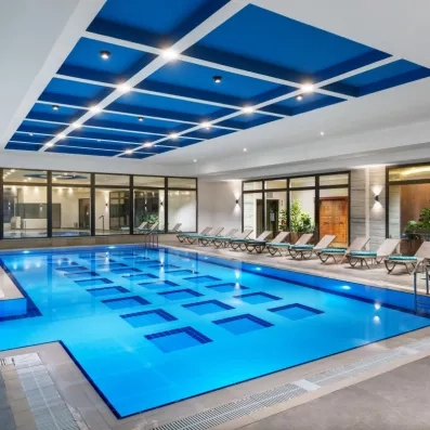 Une grande et belle piscine intérieure entourée de chaises longues.