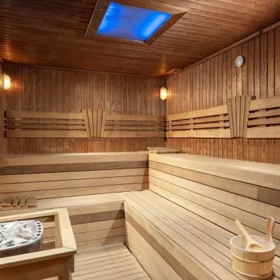 Un sauna tout en bois avec des bancs en gradins et un éclairage d'ambiance tamisé.