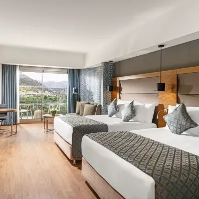 Une chambre d'hôtel lumineuse avec deux lits doubles, offrant une vue panoramique.