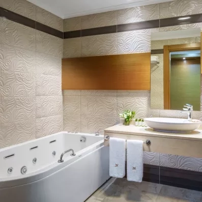 Une salle de bain équipée d'une grande baignoire balnéo et d'un lavabo blanc.