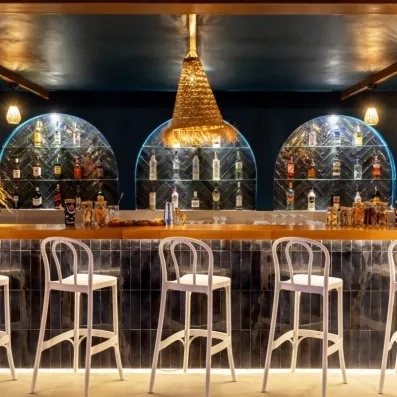 Un bar élégant au design contemporain, mettant en avant des étagères remplies de bouteilles.